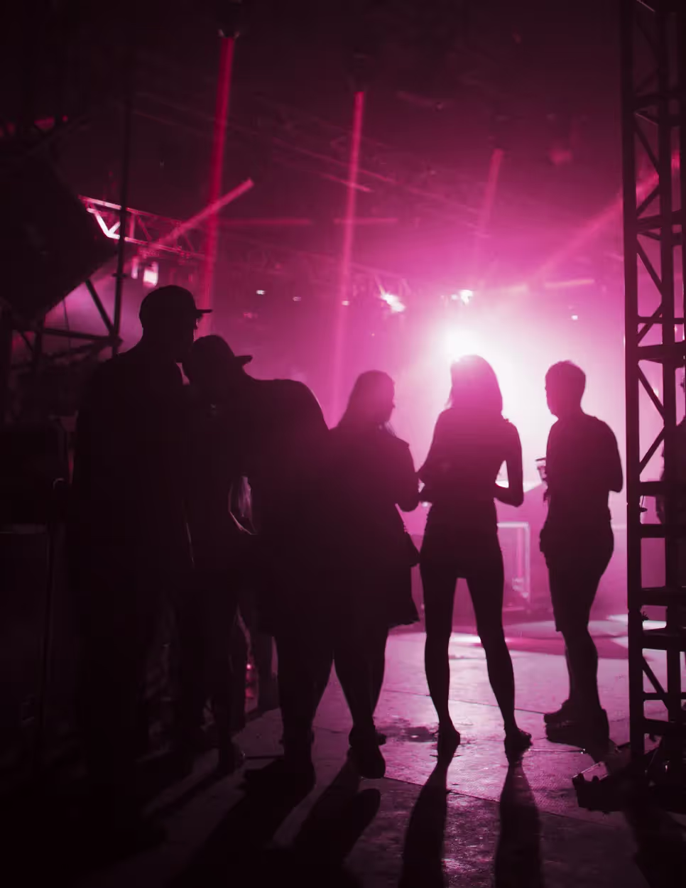 A group of people silhouetted against pink stage lights.